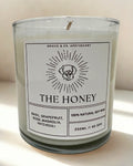 Candle labeled 'The Honey' with a label design featuring a sun and dog illustration on a white background.
