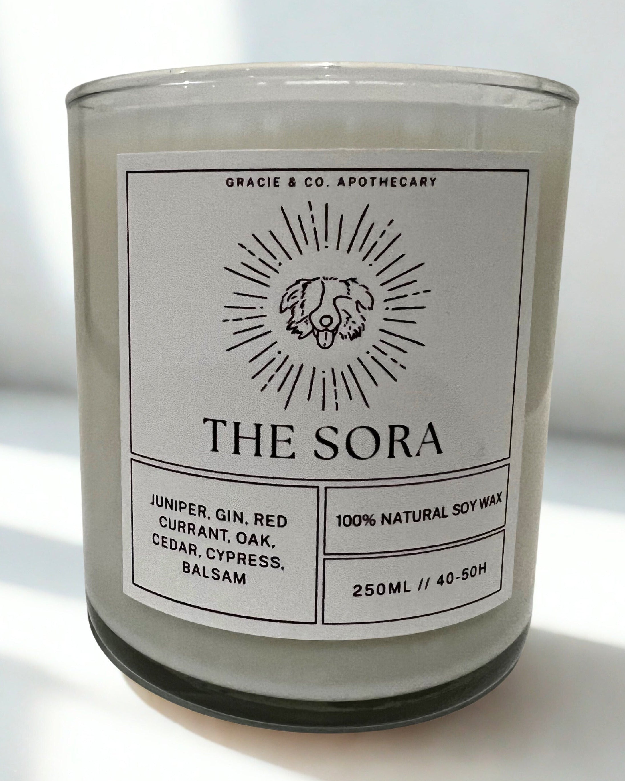 Candle labeled 'The Sora' with a label on a white surface